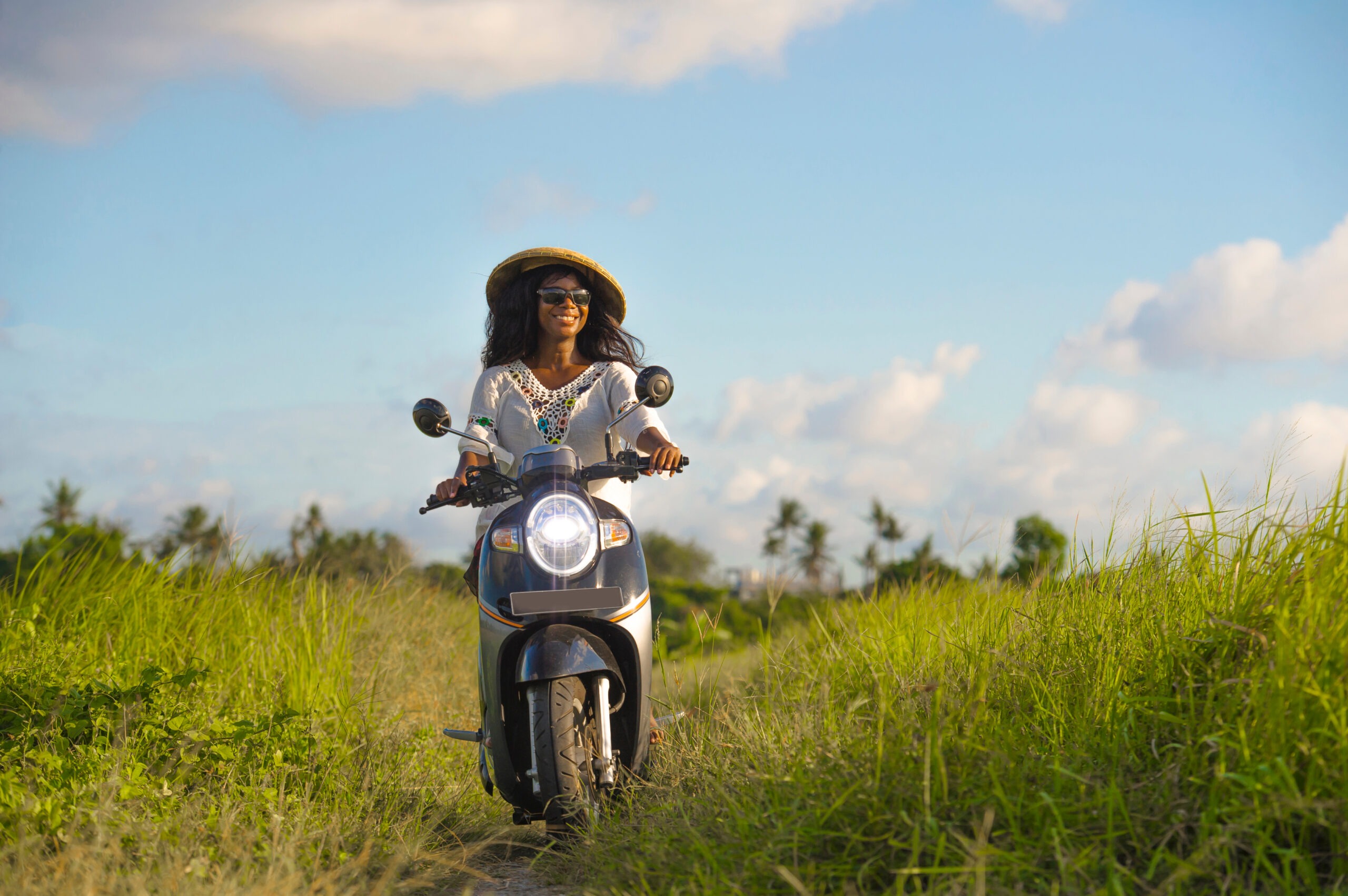 Young Beautiful Tourist or Nomad Traveler Black Afro American Woman Riding Motorbike in Tropical Field
