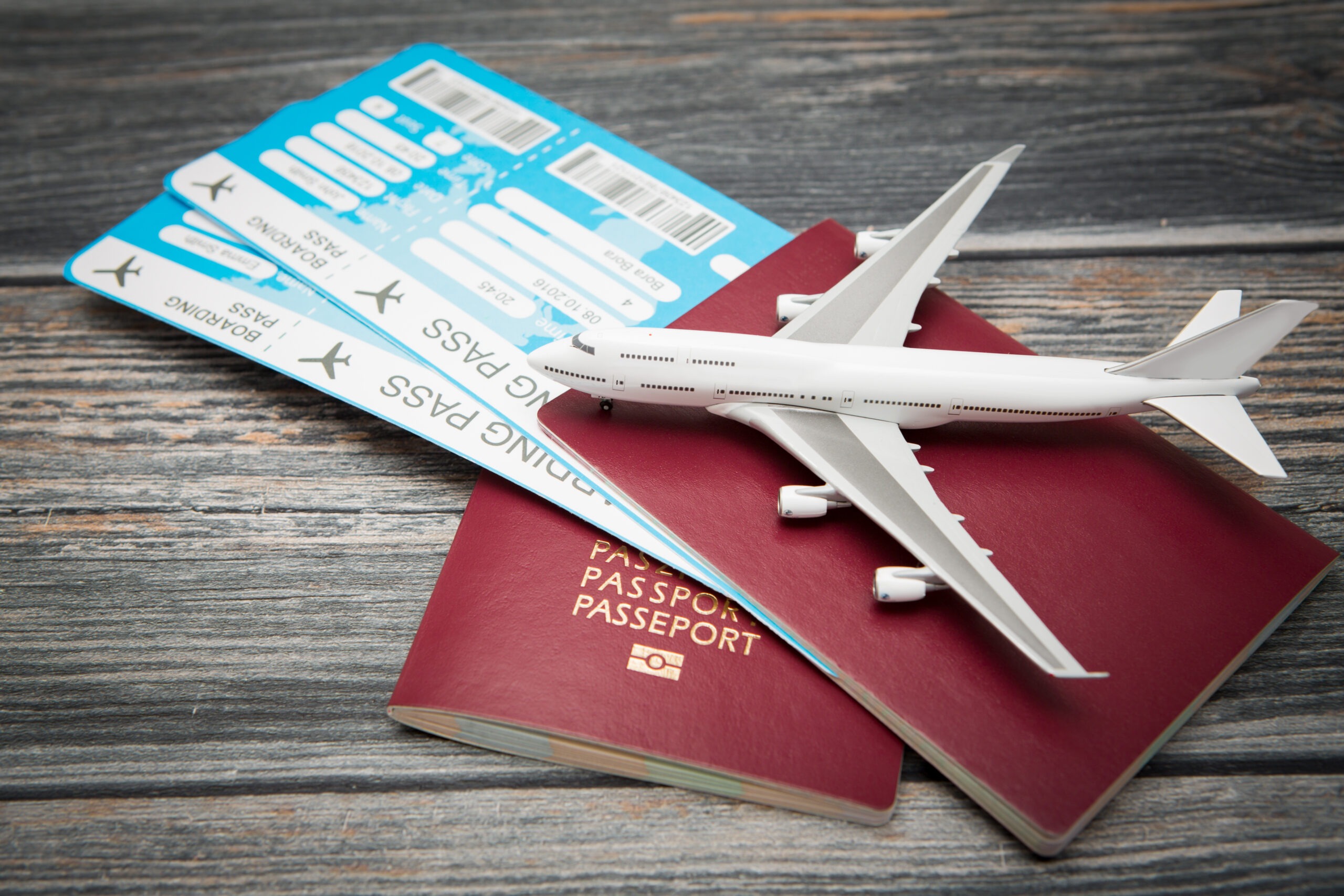 Flat Lay of Two Passports, Boarding Passes, and a Miniature Airplane Model on a Wooden Surface